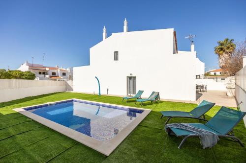 a backyard with a swimming pool and two chairs and a house at Altura Dreams in Altura