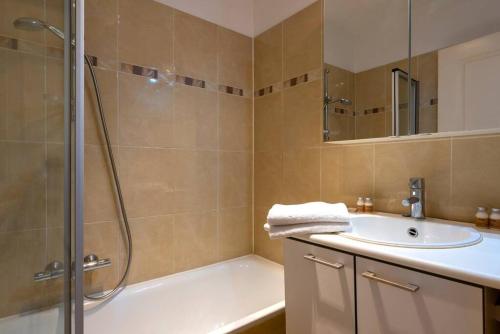 La salle de bains est pourvue d'une baignoire, d'un lavabo et d'une douche. dans l'établissement Jette Expo Duplex Residence, à Bruxelles