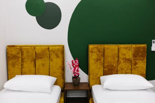 2 Betten in einem Zimmer mit grüner Wand in der Unterkunft Andor Luxury Hotel in Durrës