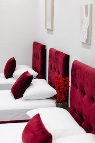 two beds with red pillows and a vase with flowers at Andor Luxury Hotel & Duplex in Durrës