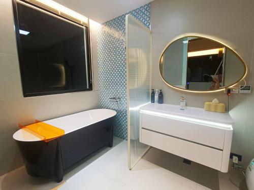 een badkamer met een bad, een wastafel en een spiegel bij 7star in Guilin