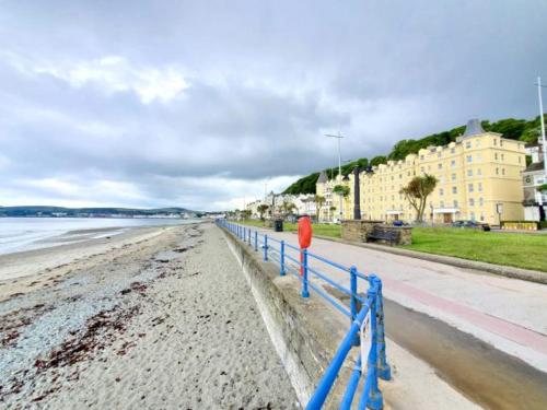 a beach with a blue fence next to the water at Edelweiss Guest House in Douglas