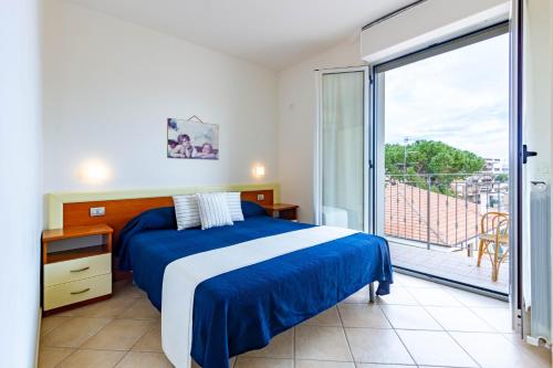 Schlafzimmer mit einem blauen und weißen Bett und einem Balkon in der Unterkunft Appartamento Pinolo Trilo INT 9 - MyHo Casa in Alba Adriatica