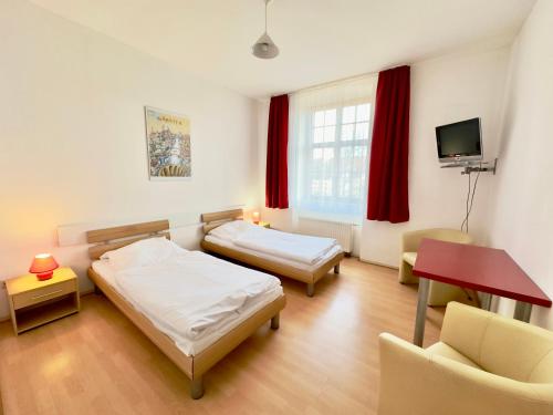 a room with two beds and a table and a tv at Picobello Pension in Görlitz