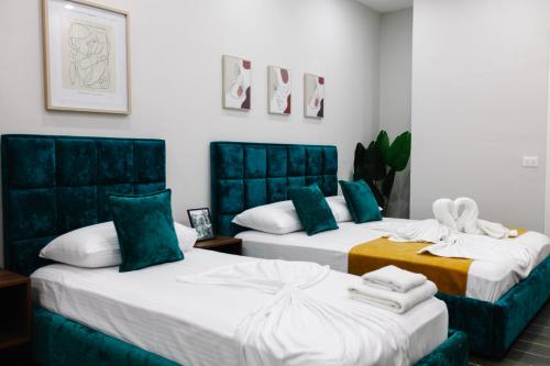 duas camas num quarto com verde e branco em Andor Luxury Hotel em Durrës