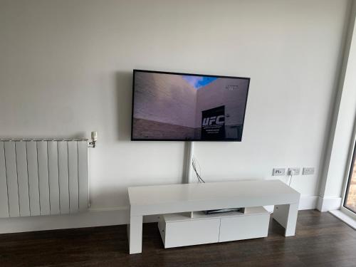 a white living room with a tv on a wall at Luxe High rise Apartment with beautiful views & free parking in Woolwich