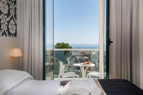 a bedroom with a bed and a balcony with a table at Hotel Villa Rosa Riviera in Rimini
