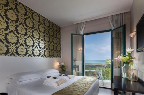 a bedroom with a bed and a large window at Hotel Villa Rosa Riviera in Rimini