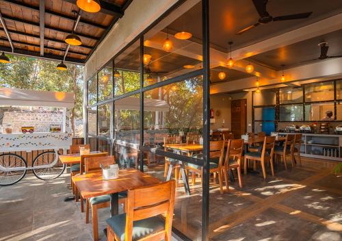 a restaurant with wooden tables and chairs and windows at Moustache Bhimtal Luxuria, Nainital in Bhīm Tāl