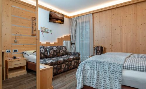 a hotel room with a bed and a couch at Hotel Aida in Pozza di Fassa