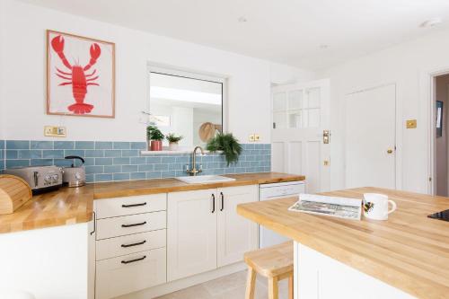 a kitchen with white cabinets and a sink and a mirror at Newly Renovated Cottage 150m from Waterfront in Bosham