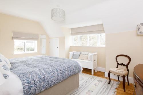 a white bedroom with a bed and a chair at Newly Renovated Cottage 150m from Waterfront in Bosham