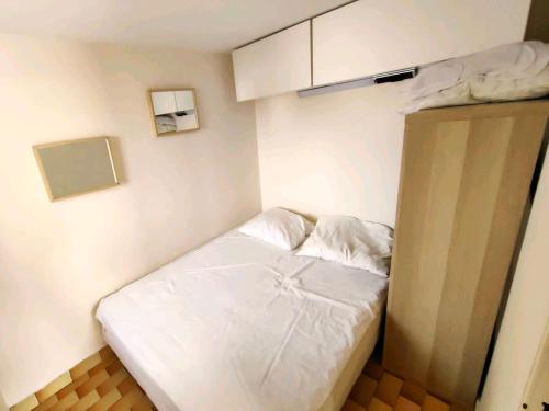 Cette petite chambre comprend un lit avec des draps blancs. dans l'établissement Charmant T2 mezzanine, 5 pers, parking sécurisé, Proche Plage & Commerces - FR-1-607-63, au Cap d'Agde