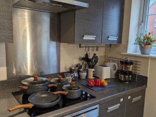 a kitchen counter with pots and pans on a stove at Sherlock's House - Two bedroom terrace 3 beds 2 sofa beds Garden Private free parking & WIFI Accessibility Contractors Family & Kids & Pet are welcome in Church Gresley