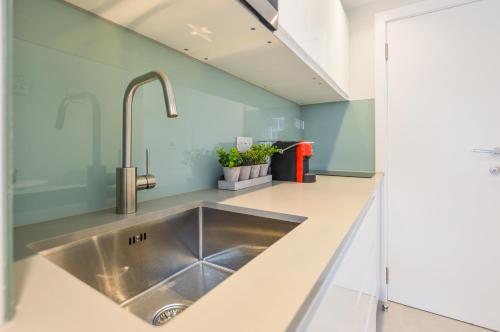 cocina con fregadero de acero inoxidable y paredes verdes en Split Level Studio at West Hampstead by Concept Apartments en Londres