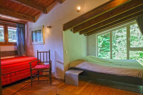 a bedroom with a bed and a chair and a window at La Maison entre Deux Rivières The River Mountain House - Nohèdes in Nohèdes