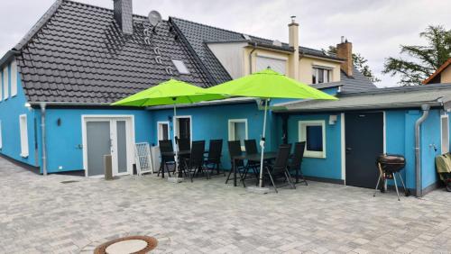 een patio met stoelen en parasols in een blauw huis bij Haus Himmelglück - Fewo Glück mit Terrasse & 2 Schlafzimmer in Zinnowitz