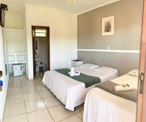 a hotel room with two beds and a bathroom at Pousada do Grande Lago in Lindóia
