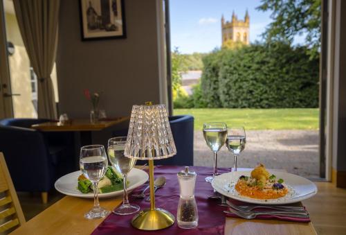 a table with two plates of food and wine glasses at Northgate House in Buckfastleigh
