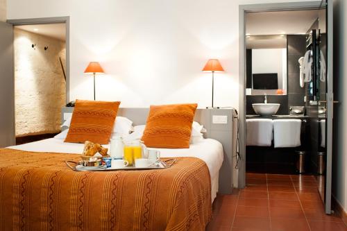 a hotel room with a bed with a tray of food on it at Hôtel Cloitre Saint Louis Avignon in Avignon