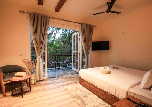 a bedroom with a bed and a balcony with a television at Moustache Bhimtal Luxuria, Nainital in Bhīm Tāl