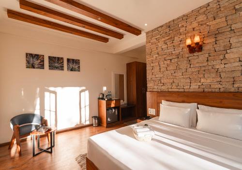 a bedroom with a bed and a brick wall at Moustache Bhimtal Luxuria, Nainital in Bhīm Tāl