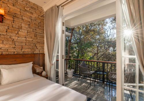 a bedroom with a bed and a balcony at Moustache Bhimtal Luxuria, Nainital in Bhīm Tāl