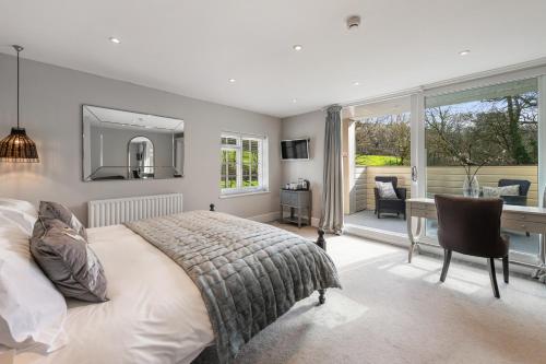a bedroom with a bed and a desk and a window at The Bickley Mill in Newton Abbot