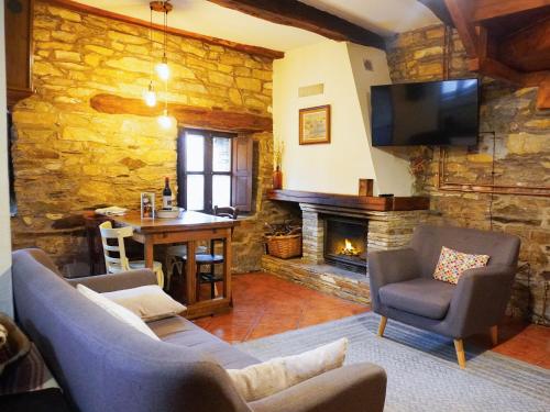 sala de estar con pared de piedra y chimenea en Fogar Mozárabe, en Peñalba de Santiago