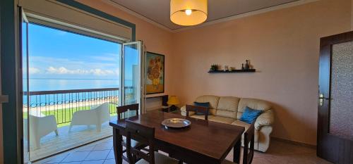ein Wohnzimmer mit Tisch und Blick auf das Meer in der Unterkunft Miramare Apartment in Acquedolci
