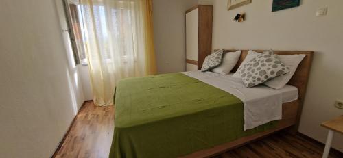 a bedroom with a bed with a green blanket and pillows at Sunce 2 in Vrbnik