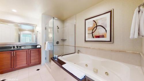 a bathroom with a large bath tub and a sink at LADY LUCK'S VISTA - Private Balcony - Full Kitchen - Two Full Baths - Jetted Tub - Full MGM Grand Resort Access w No Resort Fee at MGM Signature in Las Vegas
