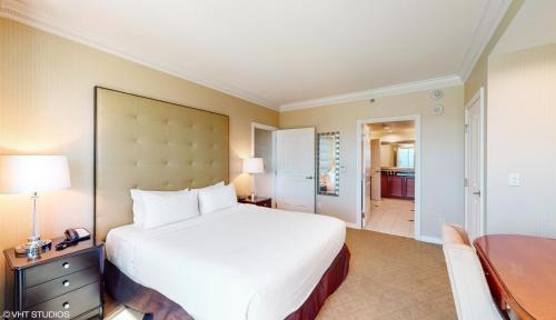 a bedroom with a large white bed and a desk at LADY LUCK'S VISTA - Private Balcony - Full Kitchen - Two Full Baths - Jetted Tub - Full MGM Grand Resort Access w No Resort Fee at MGM Signature in Las Vegas