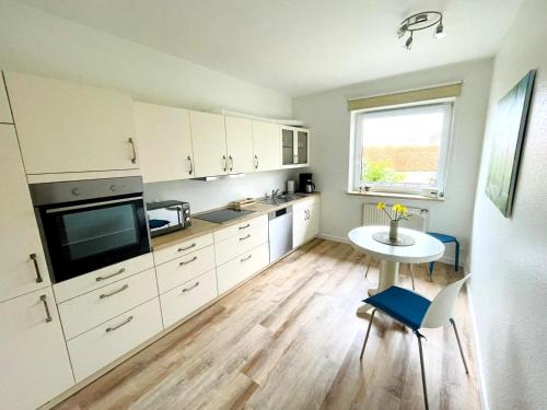 a kitchen with white cabinets and a table and a window at Schwabe, Ferienwohnung in Schneverdingen