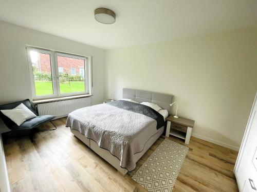 a bedroom with a bed and a chair and a window at Schwabe, Ferienwohnung in Schneverdingen