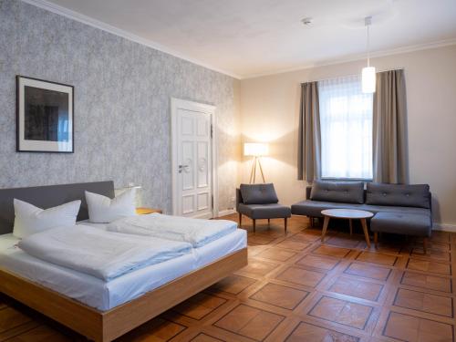 ein Schlafzimmer mit einem Bett, einem Sofa und einem Stuhl in der Unterkunft Gästehaus Nikolai in Erfurt