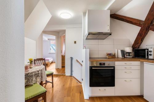 韋因斯塔特的住宿－Apartmenthaus Ferienwohnungen Sila，厨房配有白色橱柜、桌子和用餐室。