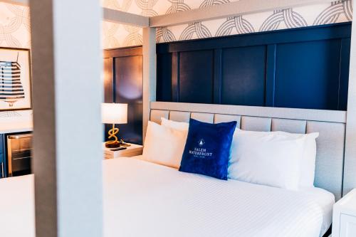 a bedroom with a bed with a blue pillow on it at Salem Waterfront Hotel & Suites in Salem