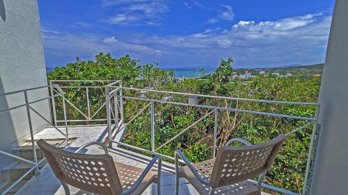 two chairs on a balcony with a view of the ocean at Coral Garden 7 Pools in Yomitan