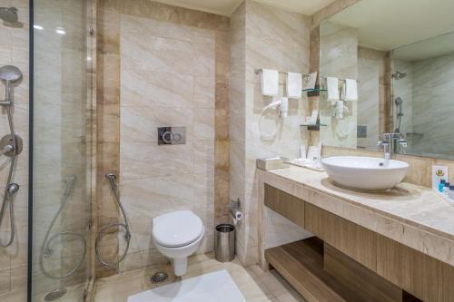 a bathroom with a toilet and a sink and a shower at Golden Suites Gurgaon Inde Hotels in Gurgaon