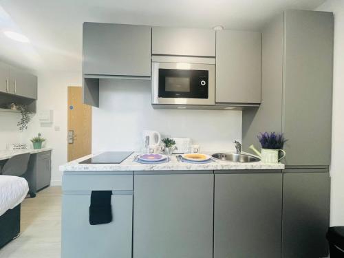 a small kitchen with a sink and a microwave at Quaint & Cosy Studio in Stretford in Manchester