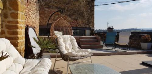 a patio with two white chairs and a table at Les Terrasses Dorées - Chambres d'hôtes de charme & Jacuzzi in Châtillon