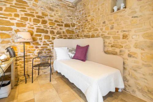 1 dormitorio con 1 cama en una pared de piedra en Les Terrasses Dorées - Chambres d'hôtes de charme & Jacuzzi, en Châtillon