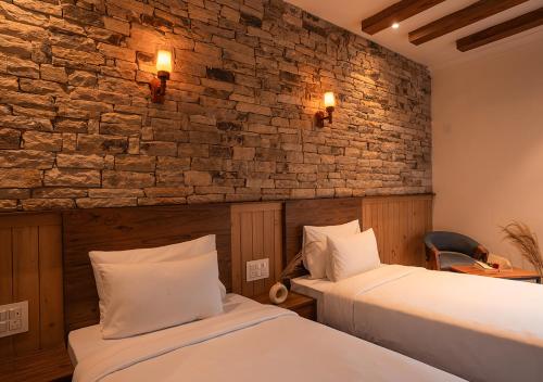 a bedroom with two beds and a brick wall at Moustache Bhimtal Luxuria, Nainital in Bhīm Tāl