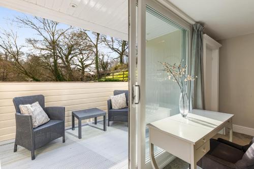 a patio with chairs and a desk and a window at The Bickley Mill in Newton Abbot