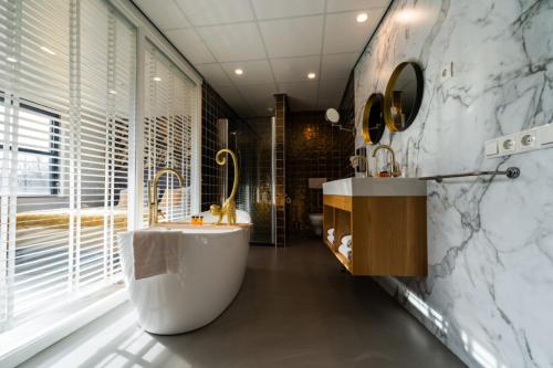 baño con bañera grande y lavamanos en Hotel WICC en Wageningen