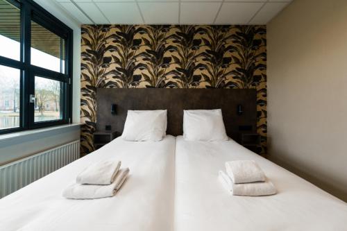 a large white bed with two white pillows on it at Hotel WICC in Wageningen