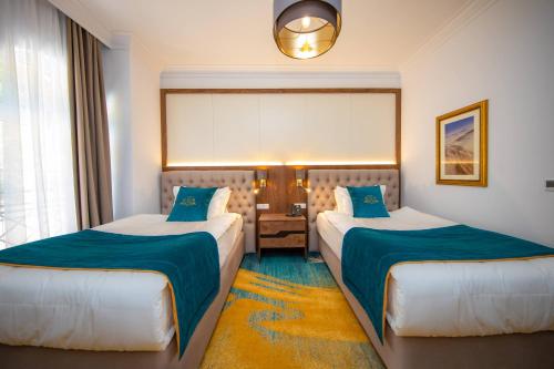a hotel room with two beds with blue sheets at Grand Hotel Belushi in Boge
