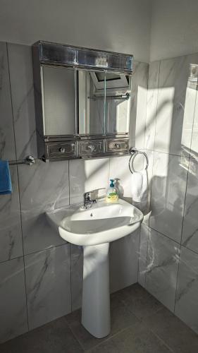 a bathroom with a white sink and a mirror at Banana Tree House in Ponta do Sol
