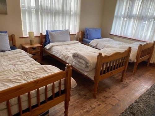 a room with three beds in a room with windows at Mount Brandon Hostel in Cloghane